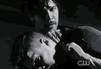 a black and white photo of a man holding another man 's neck .