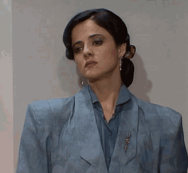 a woman wearing a blue jacket with a brooch on her shoulder
