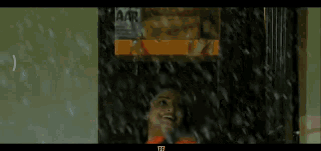 a woman in an orange dress is standing in the rain .