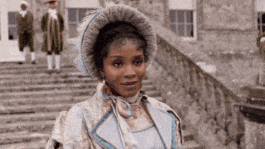 a woman wearing a feathered hat is standing on stairs