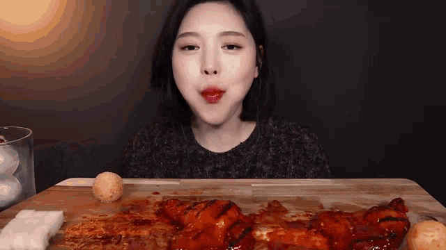 a woman is sitting at a table eating a large piece of meat .