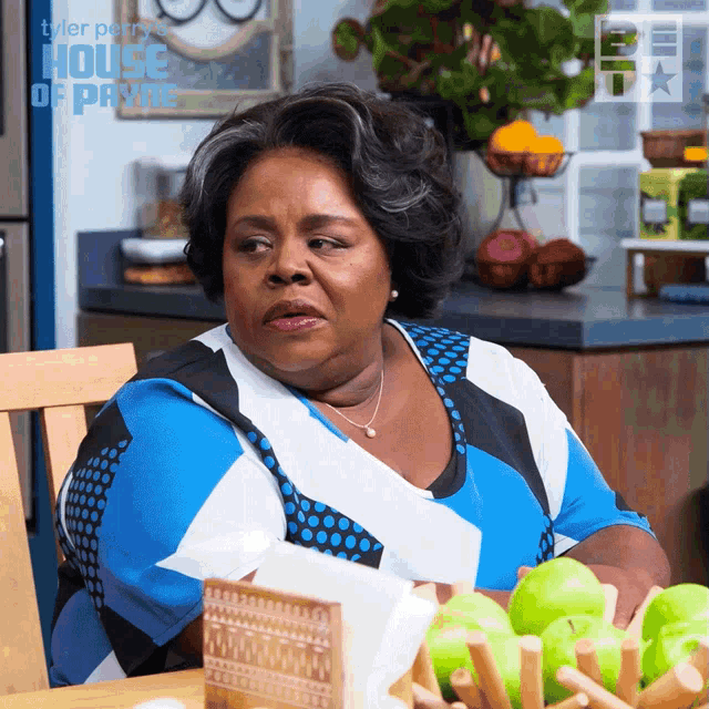 a woman sits at a table with a bowl of green apples in front of a sign that says house of payne