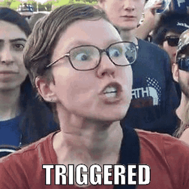 a woman wearing glasses is making a funny face while standing in a crowd .