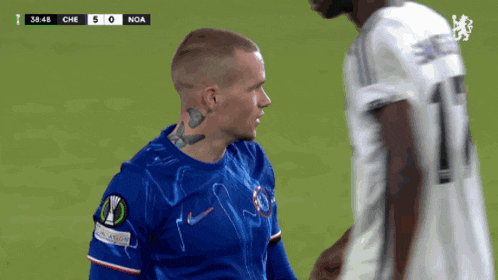 a soccer player with a tattoo on his neck talks to another player on the field