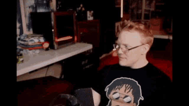 a man wearing glasses and a black shirt is sitting in front of a table
