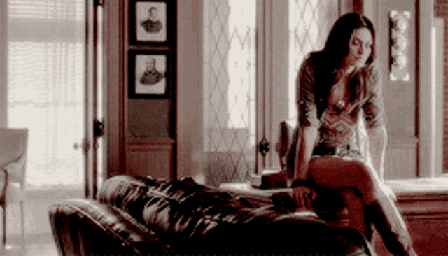 a woman is sitting on a couch with her legs crossed in a living room