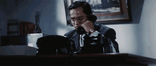 a man in a suit and glasses is talking on a phone