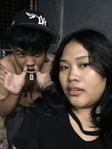 a man wearing a ny hat and a woman wearing a black shirt are posing for a picture