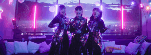 three girls are standing next to each other on a couch .