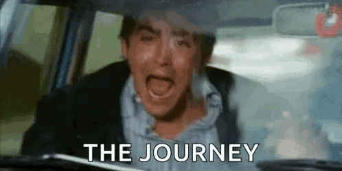 a man is crying while driving a car with the words `` the journey '' written on the windshield .