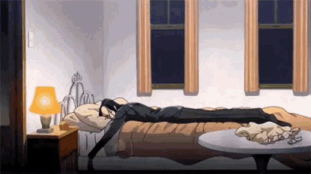 a man is laying on a bed in a bedroom with a lamp and a table .