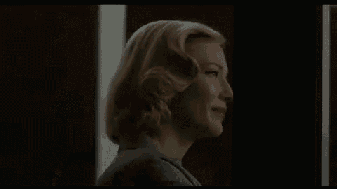 a woman with blonde hair and red lipstick is standing in front of a black wall .
