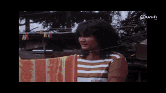 a woman in a yellow shirt hangs clothes on a line