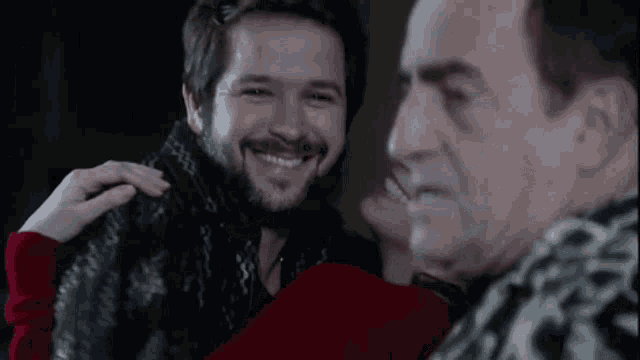 a man with a beard is hugging another man and smiling