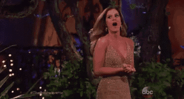 a woman in a gold dress is standing in front of a tree with her mouth open and a surprised look on her face .