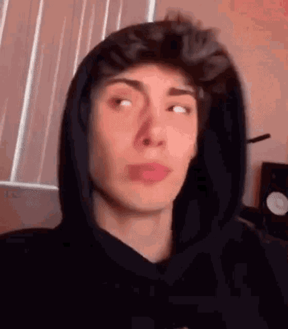 a young man in a hoodie is making a funny face .