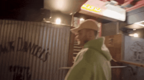 a man in a green hoodie is standing in front of a sign that says ' chase ' on it