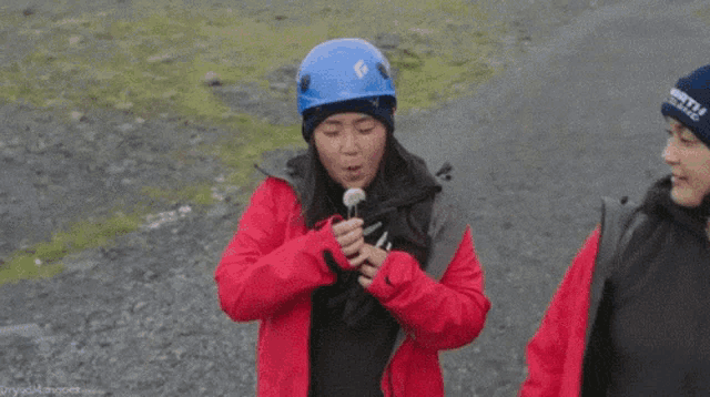a woman wearing a north iceland hat holds a small object in her hand