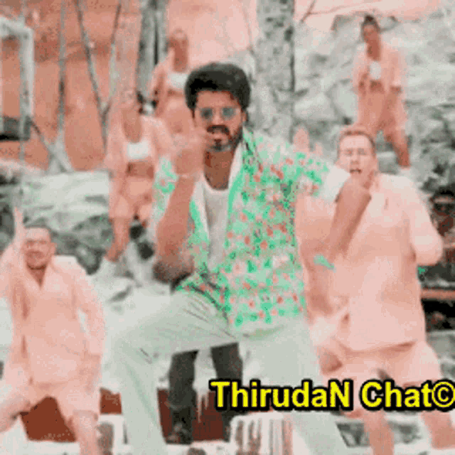 a man in a floral shirt is dancing in front of a group of people with the words thirudan chato on the bottom