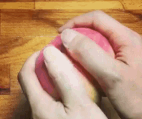 a person is holding a pink ball with their hands