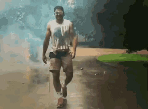 a man wearing sunglasses and shorts is walking in the rain