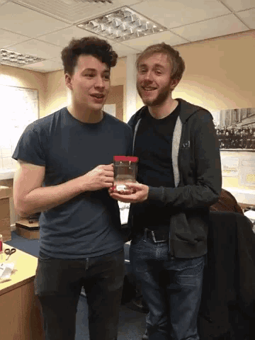 a man holding a jar of peanut butter stands next to another man
