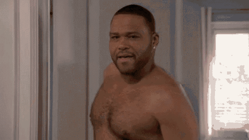a shirtless man is standing in a doorway in a room .