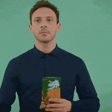 a man in a blue shirt holds a green object in his hand