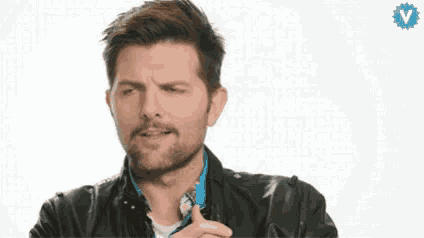 a man with a beard is holding a lollipop in his hand and making a face .