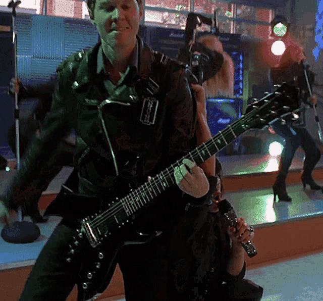 a man in a leather jacket is playing a guitar with the letter r on it