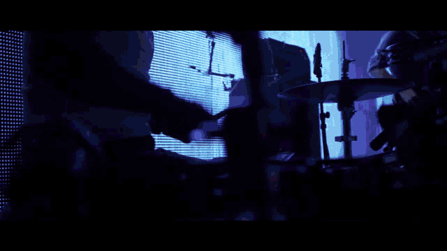 a man in a tie is playing a guitar in a dark room