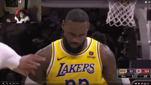 a man wearing a yellow lakers jersey looks down