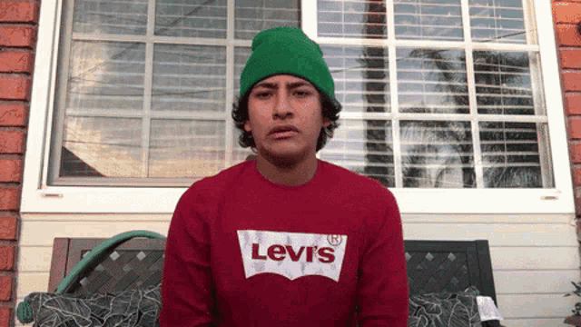 a man wearing a green beanie and a red levi 's sweatshirt