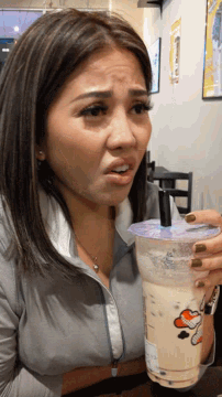 a woman is holding a cup of milk tea with a snoopy on it