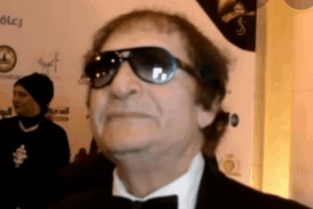 a man wearing sunglasses and a tuxedo looks up