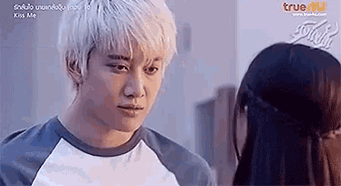 a man with white hair is looking at a woman with black hair in a room .