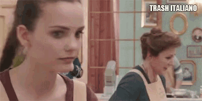two women are sitting at a table in a kitchen .