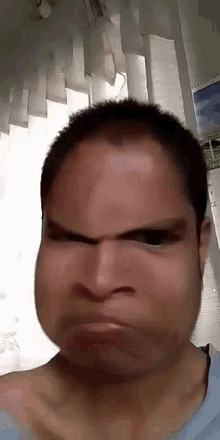 a man is making a funny face with his mouth open and his eyes closed .