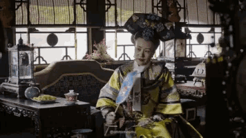 a woman in a yellow and black costume is sitting in a room holding an umbrella .