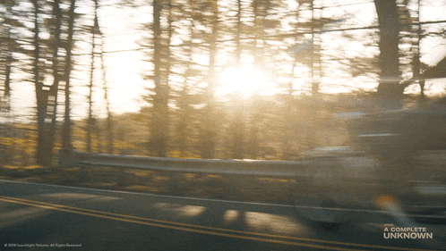 a blurred image of a road with the words a complete unknown at the bottom