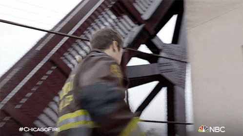 a man in a fireman 's uniform is walking across a bridge with #chicagofire on the bottom