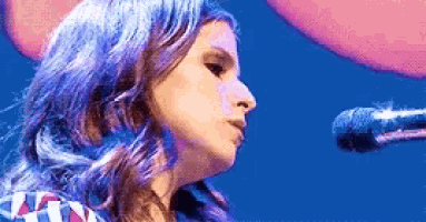 a close up of a woman singing into a microphone on a stage .