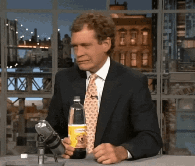 a man in a suit and tie is holding a bottle of sunkist