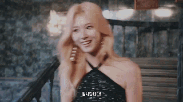 a woman in a black dress is standing on a set of stairs and smiling at the camera .