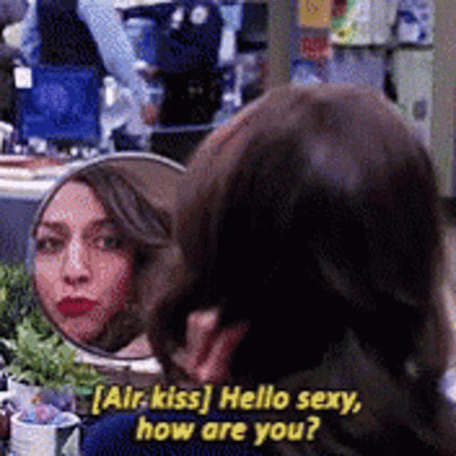 a woman is looking at her reflection in a mirror and says air kiss hello sexy how are you ?