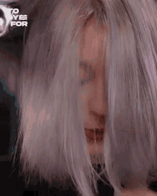 a close up of a woman with gray hair covering her face with her hair .