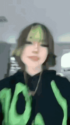 a blurry picture of a girl wearing a black sweater with green hands on it .