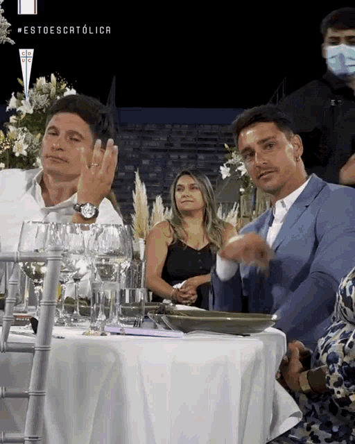 a man in a blue suit sits at a table with a white tablecloth