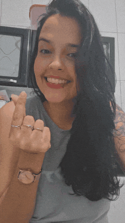 a woman wearing a watch and two rings on her fingers is smiling and giving the middle finger