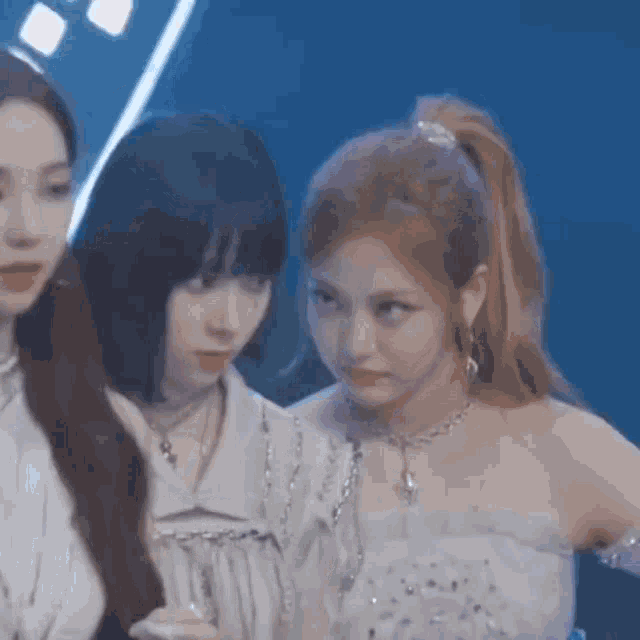 three women are standing next to each other on a stage .